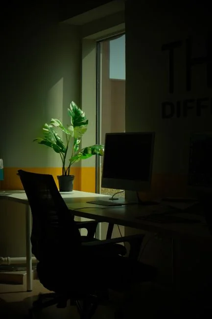 Close-up of a smartphone displaying a blurred image, placed on a desk beside a laptop.
